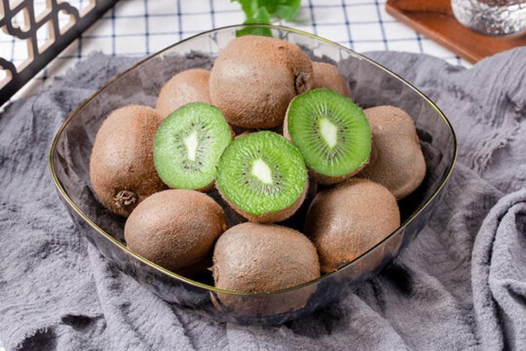 一位成年人正在用勺子从切开的翠香猕猴桃中取果肉食用