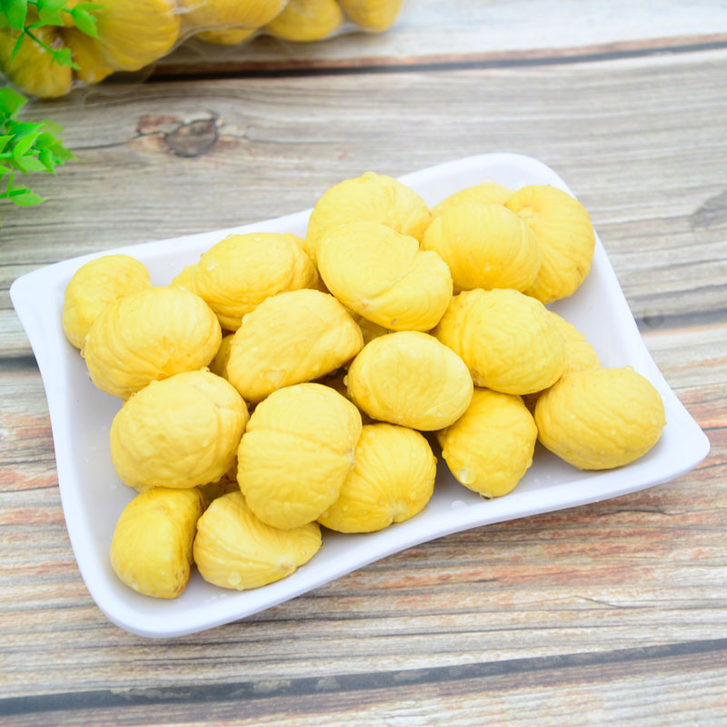 一颗完整的去壳栗子被纵向切开,清晰展示出浅黄色的果肉与紧贴其表面的深褐色内层皮,背景为木质砧板,光线柔和自然 栗子剖面展示内层皮位置