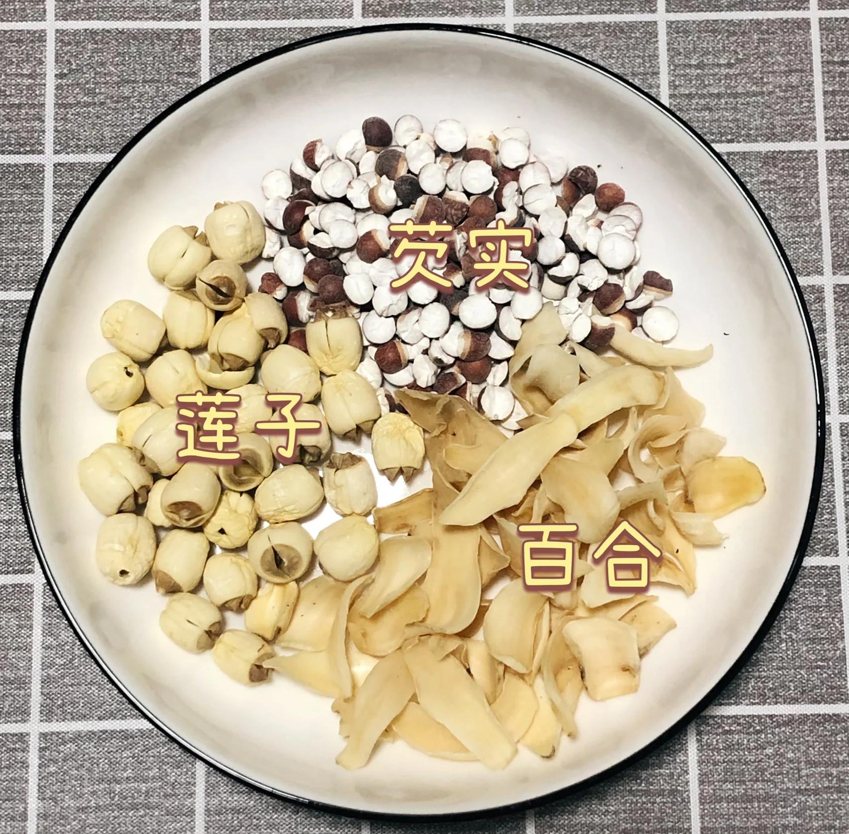中式养生厨房场景摄影:一碗温热的小扁豆百合粥为主体,呈现传统食养美学;粥液呈淡米黄色,可见完整小扁豆颗粒与半透明百合片,枸杞鲜红点染,桂花金黄细碎,佐餐萝卜条脆爽白嫩,体现平性食材的和谐配伍理念 小扁豆养生食谱场景图:青花瓷碗盛放小扁豆百合粥,粥体柔滑微稠,表面撒枸杞与桂花,旁边配小碟腌渍萝卜条与竹筷,整体色调温润雅致