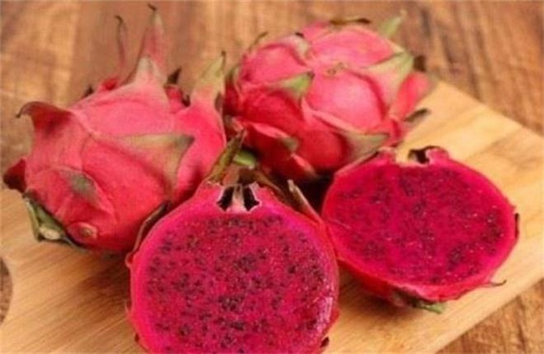 一个成熟的红心火龙果被横向切开,露出鲜艳的深紫红色果肉,黑色细小种子均匀分布,果肉饱满多汁,边缘呈波浪状,背景为浅色木质桌面,光线柔和,突出水果的色泽与质感 红心火龙果切开特写