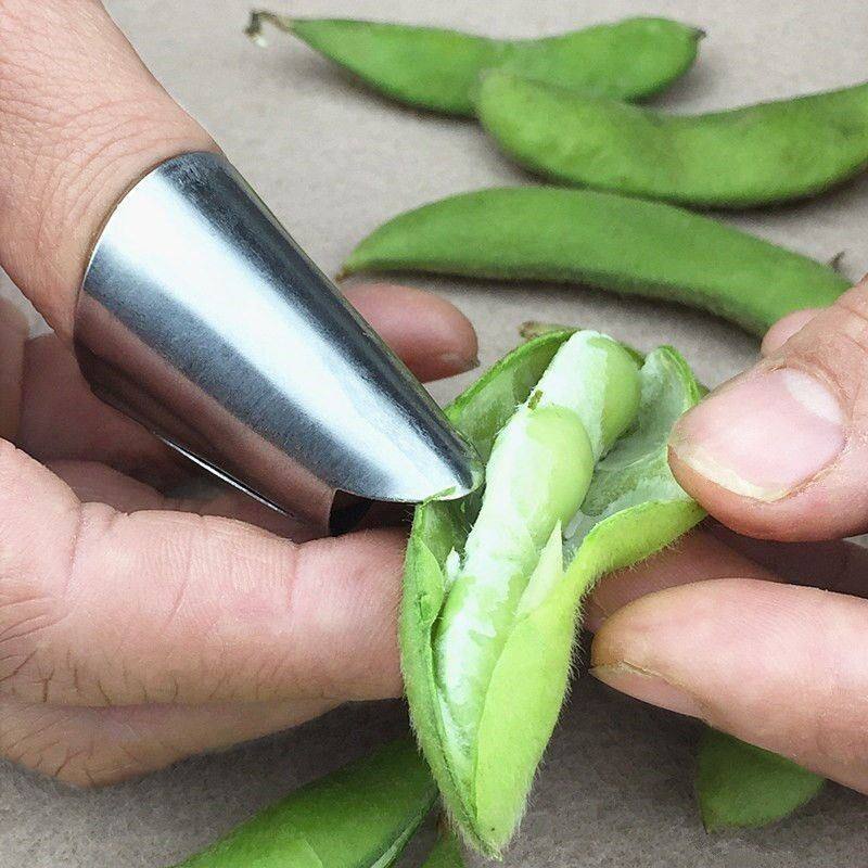 毛豆预处理步骤特写：左手持新鲜带霜毛豆荚，右手正用粗盐颗粒大力搓揉豆荚表面，背景可见白色盐粒与浅绿色豆荚对比鲜明