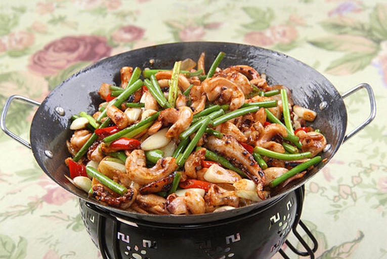 厨房中厨师正在用锅爆炒带籽鱿鱼仔