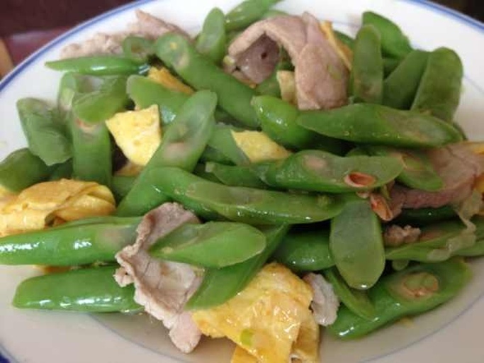 荷兰豆与新鲜鸡蛋摆放在木质砧板上，旁边有小碗盛放调好味的蛋液，背景为厨房操作台