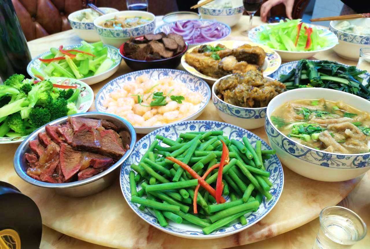 一家人围坐在餐桌前享用马肉炖土豆，桌上摆放着大碗菜肴、米饭和茶水，氛围温馨