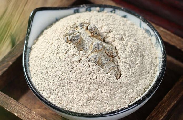 一位中年男性正在厨房中用小勺取白色至淡棕色药粉倒入透明玻璃杯,杯中有少量温水,旁边放置密封玻璃罐装药粉,标签注明‘丹参三七红参复合粉’,环境整洁明亮,体现健康生活方式 丹参三七红参粉剂冲泡场景图