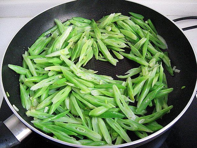 厨房中正在翻炒荷兰豆的过程