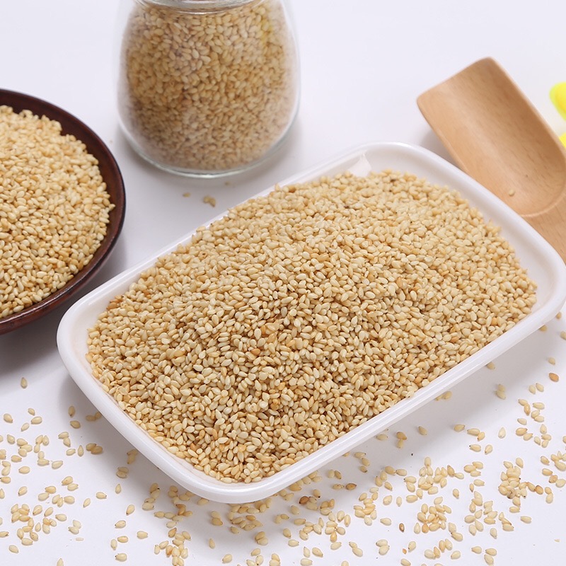 一组展示焙煎芝麻不同应用形式的照片:左侧为玻璃瓶装的芝麻酱,中间为撒满芝麻的拌饭,右侧为棕色纸托上的芝麻能量球,背景为原木色托盘和绿色植物,整体风格清新自然 焙煎芝麻系列产品组合图