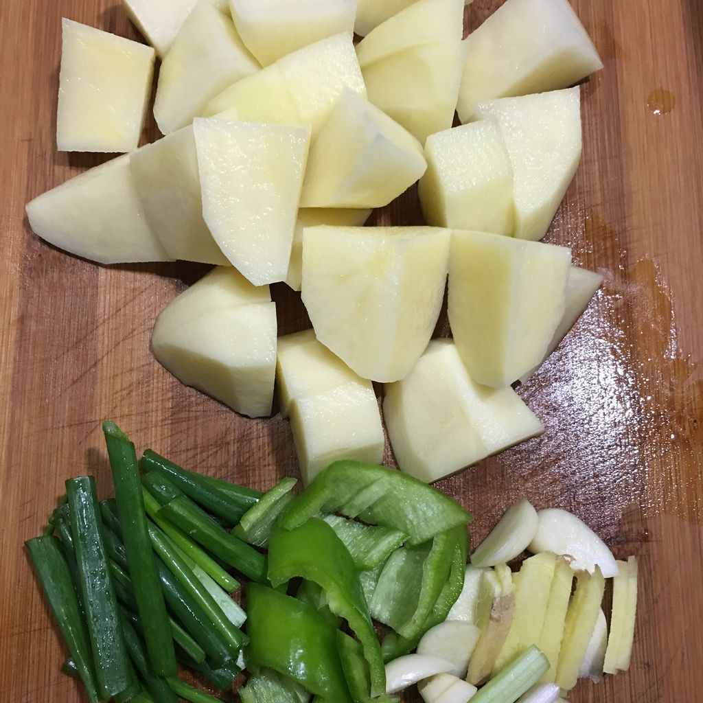 荷兰豆和土豆的食材准备,包括已去筋的荷兰豆、切片浸泡后的土豆、蒜片、姜丝和干辣椒 荷兰豆和土豆的食材准备