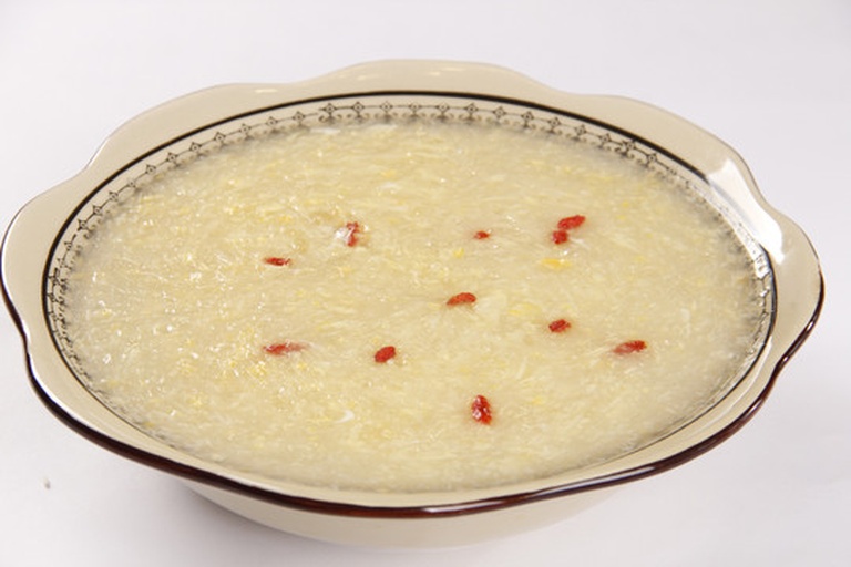 一只白色陶瓷小碗中盛着刚出锅的五味子蒸蛋,表面光滑如镜,微微颤动,蛋羹呈浅黄色,内嵌细碎红褐色五味子颗粒,顶部点缀三颗鲜亮枸杞,边缘滴有晶莹香油,背景虚化,突出食物质感与食欲感 五味子蒸蛋成品特写