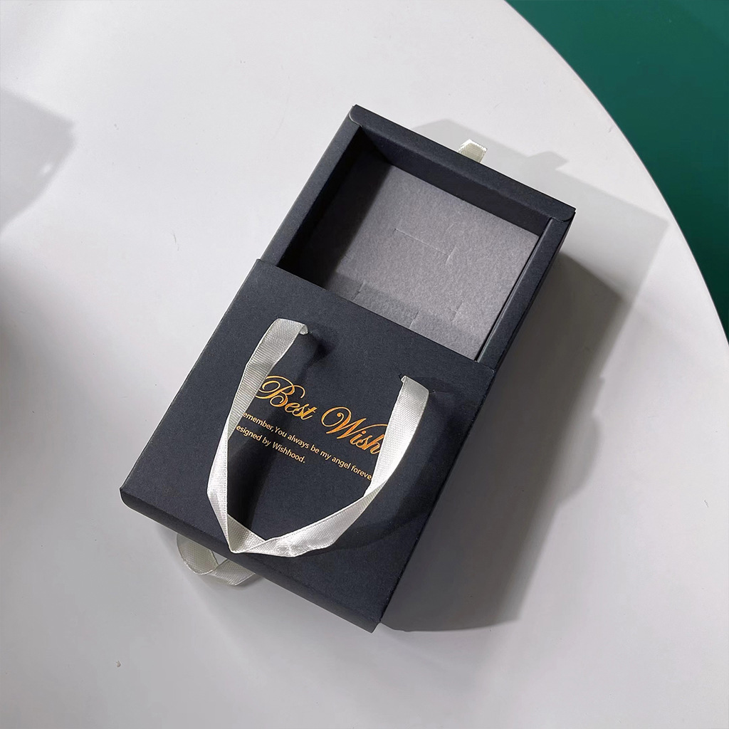 一张白色桌面上摆放着三款不同风格的手指红提礼盒:左侧为木质翻盖礼盒内衬绒布,中间为透明开窗纸盒印有‘十指紧扣’烫金字样,右侧为真空独立小包装组合装,旁边配有品牌LOGO卡片和丝带装饰 手指红提礼盒展示