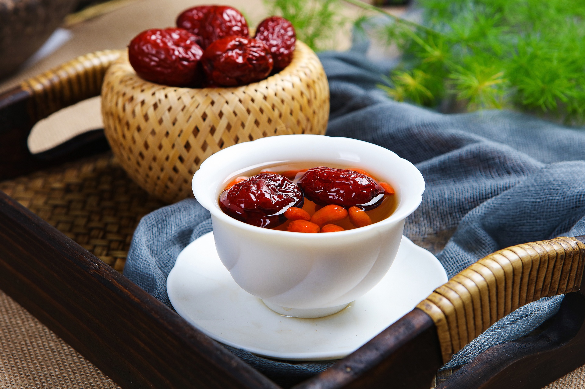 一张圆形拼盘展示干红枣片与枸杞、桂圆、菊花、银耳等常见养生食材的搭配组合,背景为中式茶具与养生茶饮,体现日常饮用场景 红枣养生搭配示意图