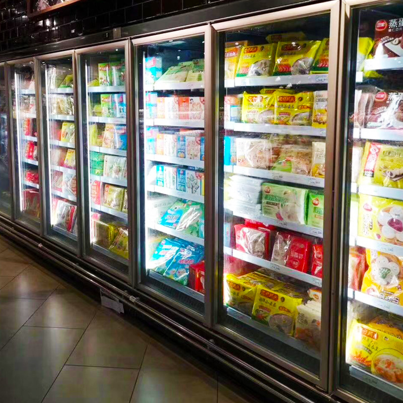 一家大型超市的冷冻食品区,开放式冷柜中整齐陈列着不同品牌的冷冻蔬菜组合包,其中包括标明‘甜豌豆’‘混合豆仁’等产品,包装透明可见内容物,冷柜表面有轻微霜迹,顾客正在挑选,环境整洁明亮 超市冷冻区货架展示各类冷冻蔬菜包
