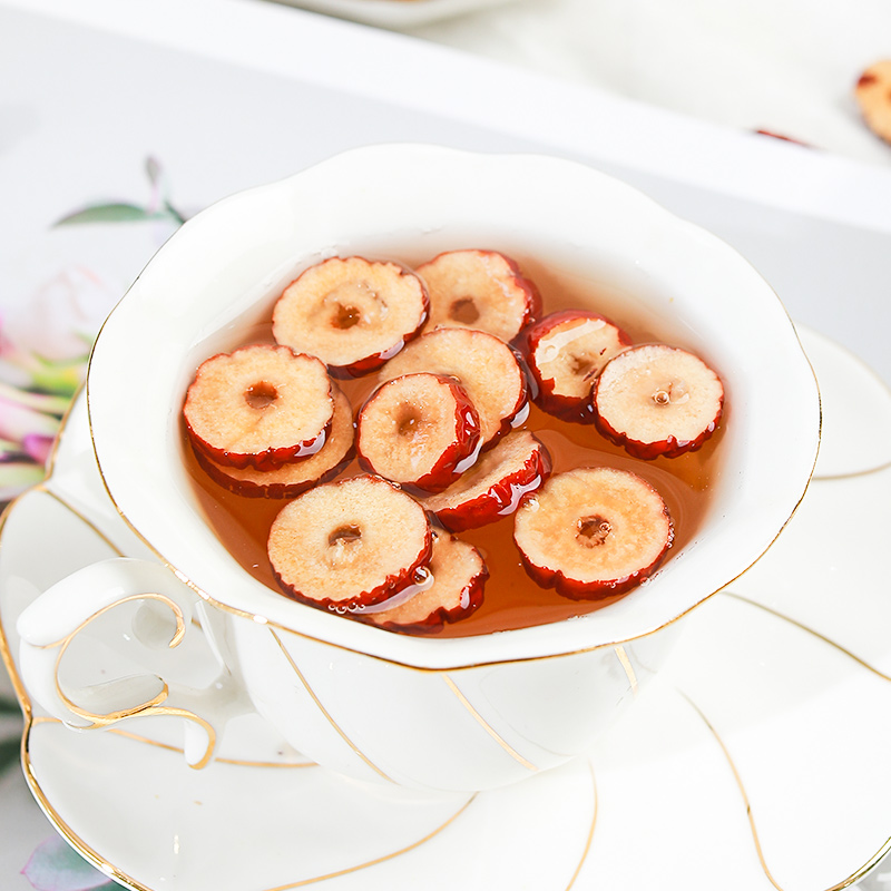 家用破壁机正在研磨冷冻红枣片：玻璃杯体中可见浅褐色粉末缓慢旋转，刀片边缘无明显黏附，机身上方有轻微白雾（冷凝水汽），显示低温运行状态