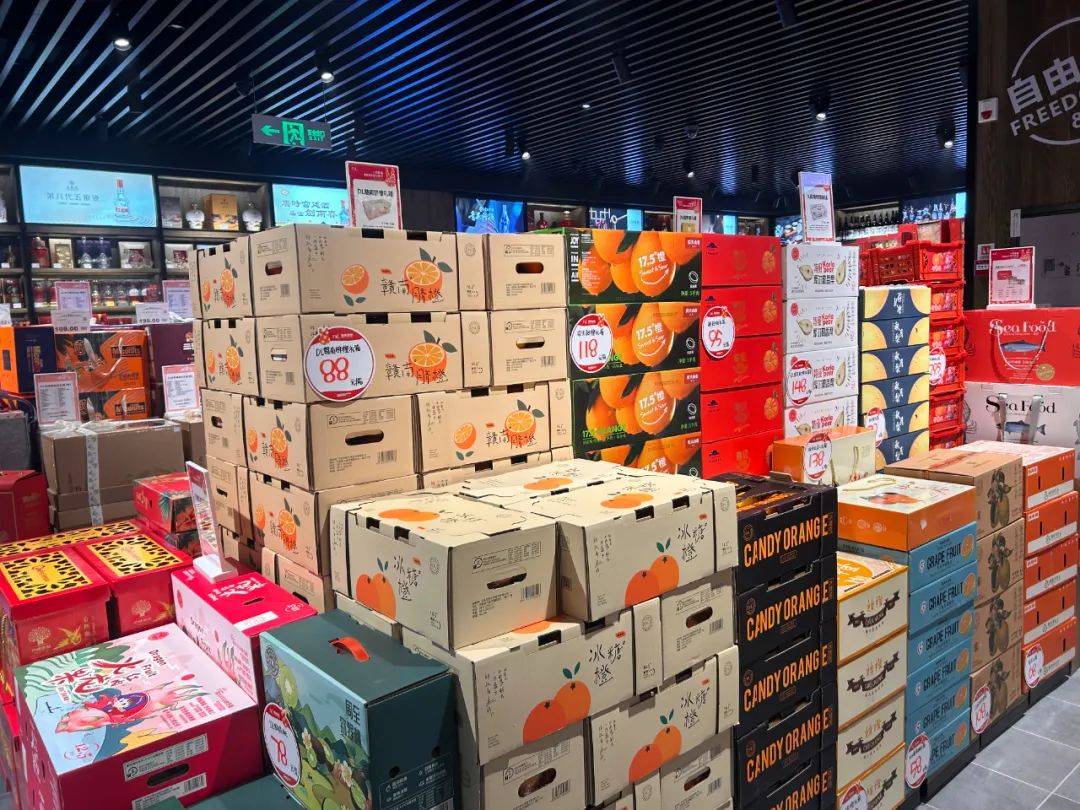 现代超市货架上摆放着印有‘冰凌橙夏’品牌的礼盒装橙子,旁边是透明塑料盒装的果切产品;另一侧展示电商平台打包场景,工作人员正在将橙子放入定制纸箱,附带冰袋和品牌宣传卡 冰凌橙夏电商包装与线下陈列