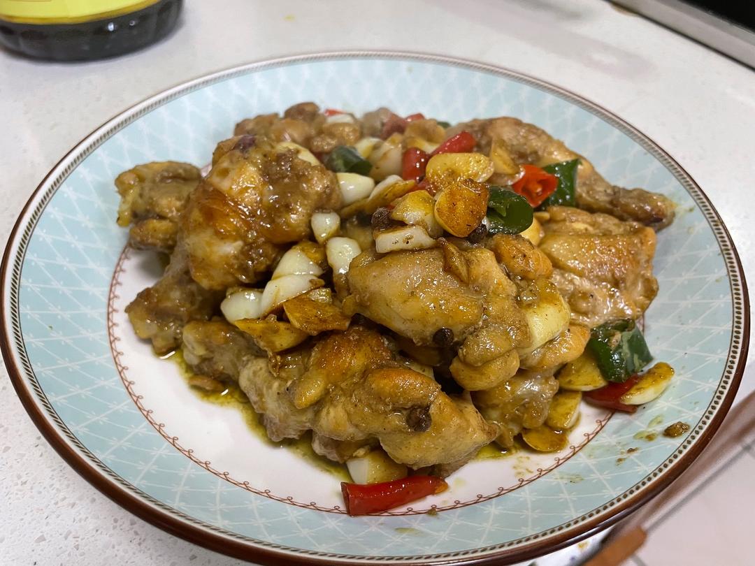 一盘刚出锅的蒜香鸡片,鸡肉呈乳白色,裹着晶莹酱汁,青红椒鲜艳点缀其间,蒜片金黄分布均匀,整体色泽明亮诱人,盛放在白色瓷盘中 蒜香鸡片成品图
