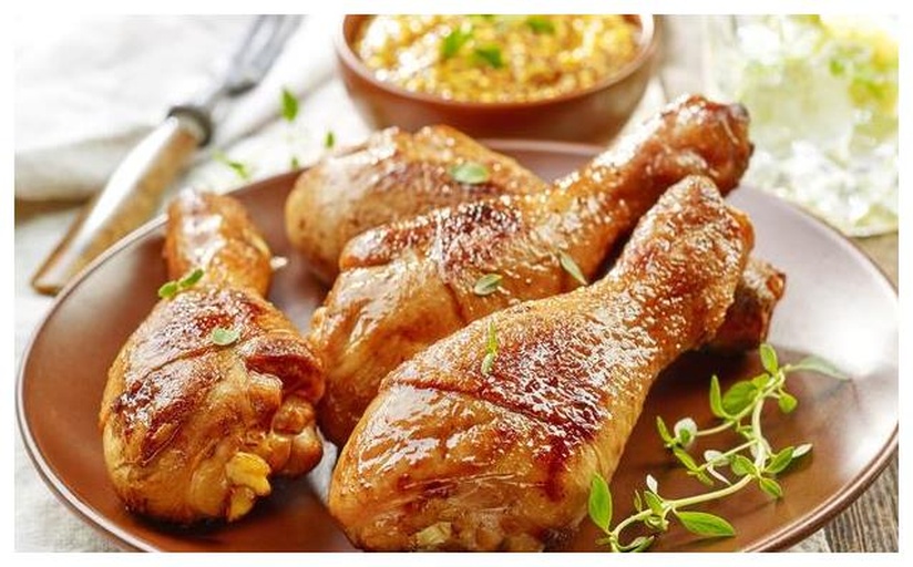 一只特写镜头下的烤鸡腿横放于木质砧板上，鸡腿表皮呈琥珀色带焦糖斑纹，油光润泽，可见清晰肌理；旁边并排摆放两根去叶留白的大葱段，葱白饱满瓷实、泛青玉光泽，切口新鲜湿润；背景虚化处隐约可见炭火余烬与铁网烤架