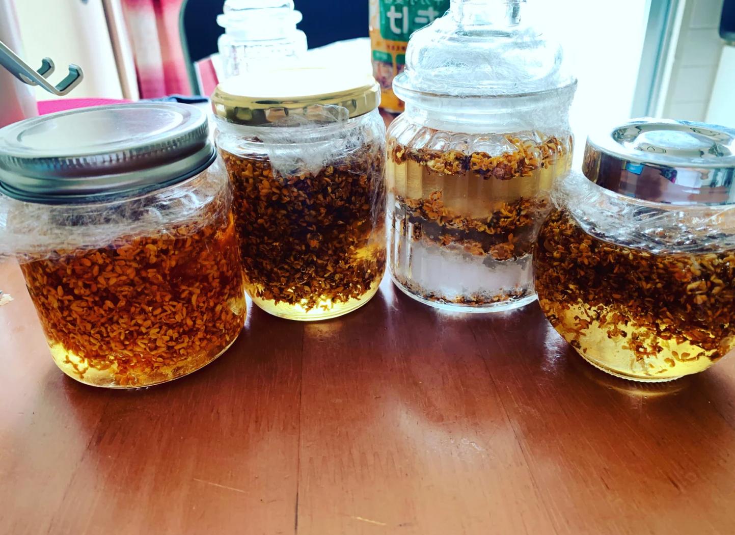 玻璃密封罐内装有金黄色油醋汁，正在被手摇晃，液体呈乳化状态