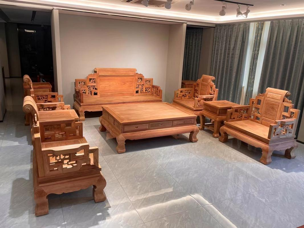 一套由非洲金花梨制成的新中式风格客厅家具,包括沙发、茶几和边柜,木材表面呈现柔和的金黄色调与深色条纹交织的纹理,经过精细打磨和清漆处理,展现出温润光泽,置于现代家居环境中 非洲金花梨家具成品展示