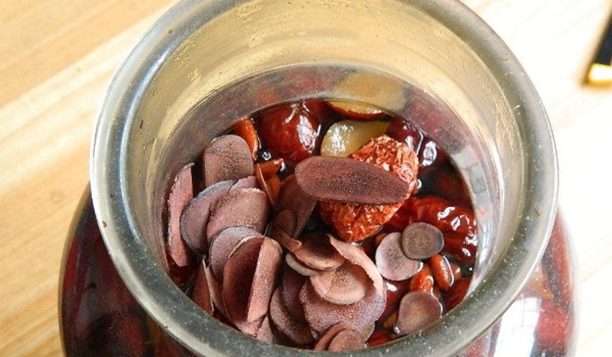 一张横向排列的玻璃罐装食品对比图,包含黑枣、红枣、核桃、杏仁、枸杞,每个容器贴有标签注明名称与热量值(千卡/100克),背景为浅灰色厨房台面,光线柔和,突出营养可视化概念 黑枣与其他坚果干果对比图