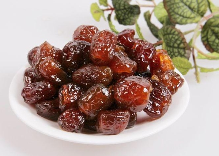 展示一盘新鲜制作的黏枣,色泽红润,质地柔软,表面微微泛糖光,背景为农家厨房环境 黏枣特写展示