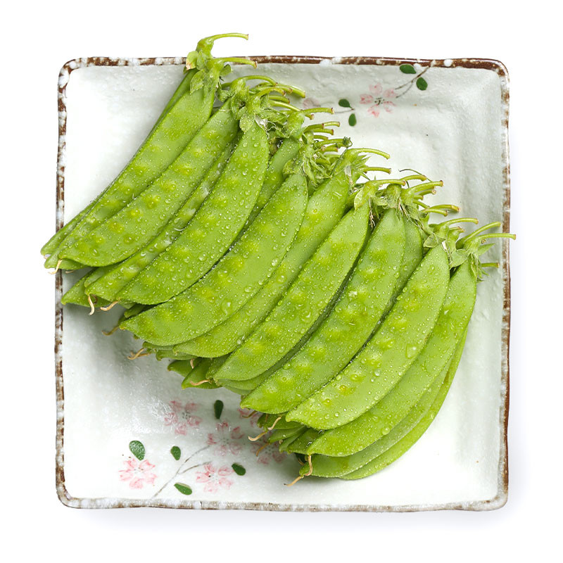 一盘刚出锅的蒸白不老豆角盛放在青花瓷盘中,豆角颜色碧绿油亮,表面略带光泽,旁边点缀几片红辣椒和香菜叶,背景为木质餐桌与粗陶碗筷,整体呈现温馨农家用餐氛围 成品蒸白不老豆角摆盘效果