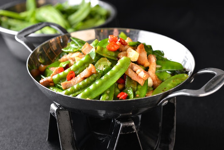 家庭厨房中正在翻炒荷兰豆的场景