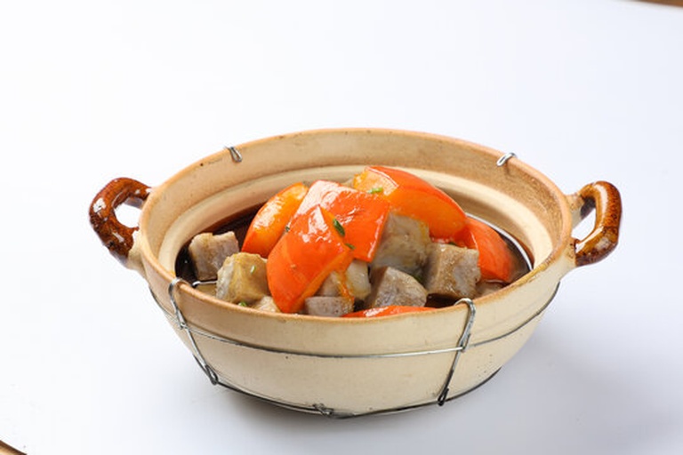 一个不锈钢锅中正在炖煮红色浓稠的番茄炖菜,内含土豆、胡萝卜和少量肉类,蒸汽袅袅升起,旁边放有木勺和新鲜番茄作为装饰,体现家常健康烹饪氛围 家庭厨房中的番茄炖菜场景