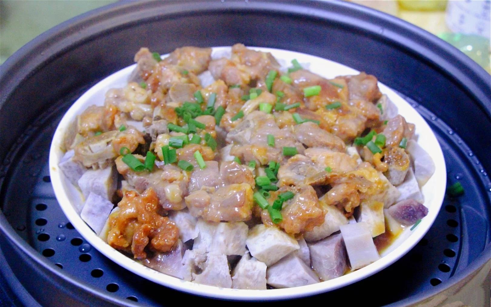 成品香芋蒸排骨俯拍特写，金棕色排骨整齐铺于粉紫色香芋块上，表面油润反光，蒸汁清澈微稠，零星葱花点缀，热气氤氲