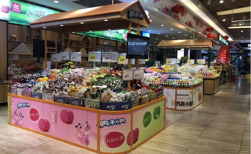 现代超市冷柜中整齐摆放的百香果盒装产品,左侧标签标注‘黄金百香果’,右侧为‘紫红百香果’,旁边有手机屏幕显示电商平台下单页面,体现线上线下融合消费场景 百香果在超市货架与电商包装中的陈列实景
