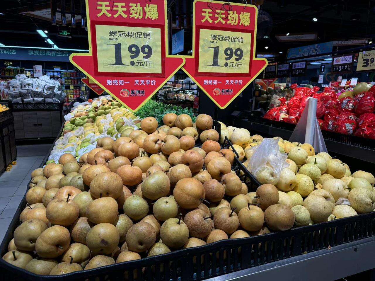 一个热闹的农贸市场中,摊主正在整理一筐筐新鲜的皇冠梨,梨子整齐摆放,颜色鲜亮,顾客正在挑选购买,背景有价格标签‘皇冠梨 5元/斤’,体现真实消费场景 市场中售卖皇冠梨的摊位场景