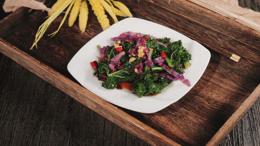 一组摆放整齐的甘蓝类蔬菜,包括绿色卷心菜、紫色甘蓝、羽衣甘蓝和西兰花,背景为浅色木纹桌面,光线明亮自然,突出各类蔬菜的颜色与形态差异 多种甘蓝类蔬菜组合图