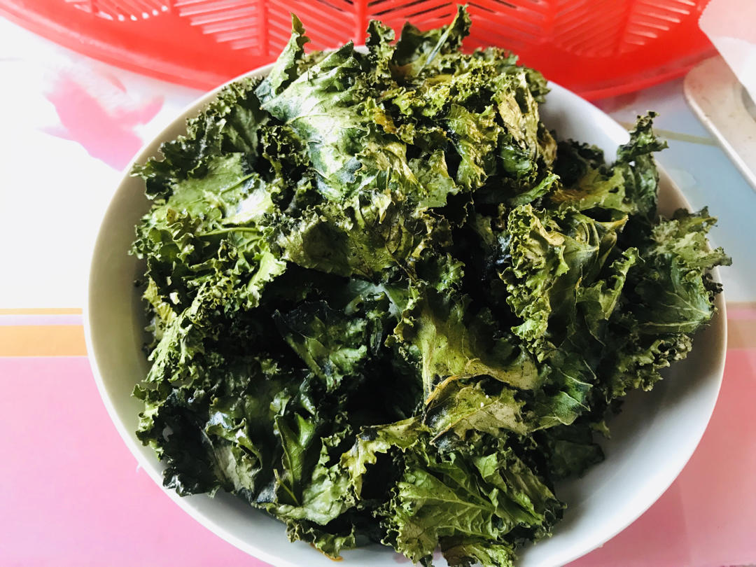 一盘精致摆盘的水煮羽衣甘蓝,翠绿色叶片整齐排列于白色瓷盘中,表面淋有少许橄榄油光泽,旁边点缀柠檬片和蒜末,背景为木质餐桌,风格清新自然 成品水煮羽衣甘蓝摆盘图