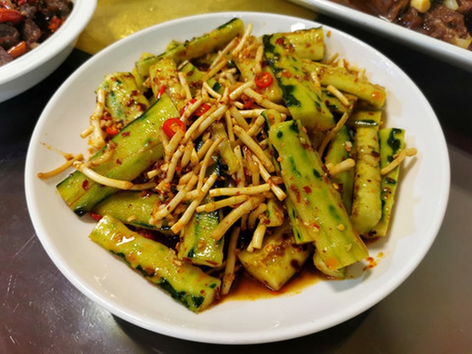 一盘凉拌黄瓜木耳特写，黑木耳卷曲有光泽，黄瓜呈块状分布，表面有蒜末和红椒丝点缀，盛于浅色陶瓷碗中