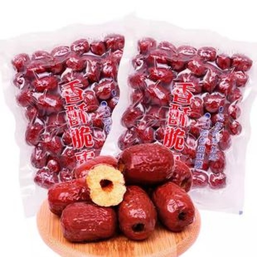 一台白色家用真空封口机正在对装有干红枣片的透明袋子进行抽气封口,桌上散落着待处理的红枣片和空袋,展示现代化食品保存方式 真空封口机操作示意图