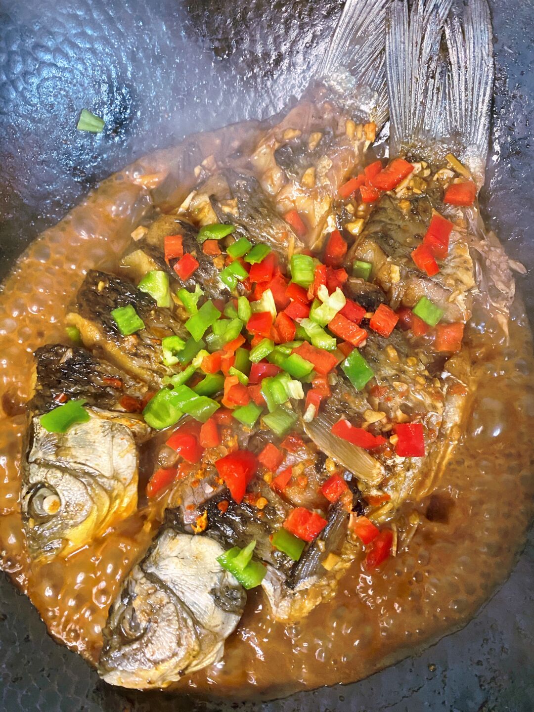 一盘完成的红烧鱼被端上餐桌,鱼身完整,表面覆盖着红亮的酱汁,顶部撒满了翠绿的小葱末,旁边配有白米饭和青菜,光线柔和,突出食物的诱人质感 图片描述