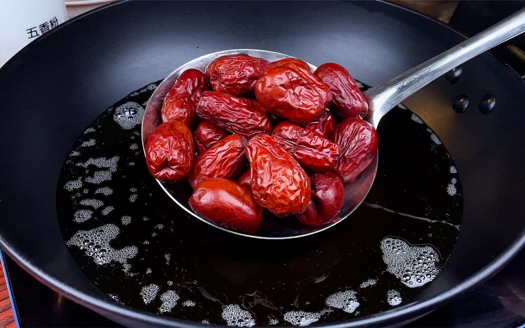 金黄色的红枣正在热油中翻滚,油面泛起细密气泡,使用透明玻璃炸锅拍摄,可见红枣形态完整,色泽渐变为琥珀金,背景虚化的温度计显示165℃ 脆枣油炸过程特写