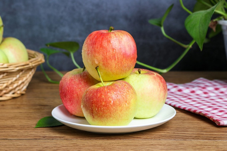 一组摆放在白色瓷盘中的低钾水果:切块苹果、梨片、葡萄、菠萝丁和西瓜瓣,背景为淡绿色厨房布景,象征健康饮食环境 低钾水果组合图