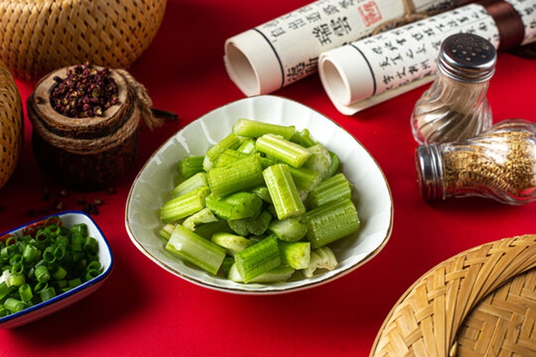 一张整洁的木质桌面上陈列着多种以芹菜籽为原料的深加工产品:玻璃瓶装有机芹菜籽、胶囊瓶、深棕色冷压油滴管瓶、纸袋装芹菜籽粉、以及搭配柠檬片与香草束的摆拍元素,整体风格偏向自然健康,适合电商主图使用 芹菜籽深加工产品陈列图