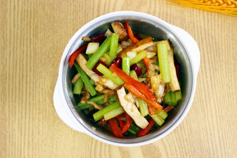 一盘刚出锅的芹菜炒羊肉,绿色芹菜条与棕红色羊肉片交错分布,表面略带油光但不过腻,配有白芝麻点缀,盛放在浅灰色陶瓷盘中,背景为简约中式餐桌 芹菜炒羊肉成品菜肴展示