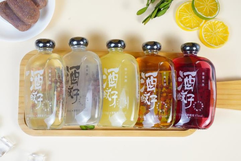 一个宽敞明亮的厨房操作台上摆放着多个大小相同的透明广口玻璃瓶,每个瓶中均装有淡黄色酒液,清晰可见内部浸泡的柠檬切片和结晶冰糖颗粒,瓶口配有橡胶密封圈和不锈钢旋盖,标签纸上手写着‘柠檬酒 - 2024年6月’字样 家庭自制柠檬酒浸泡过程图