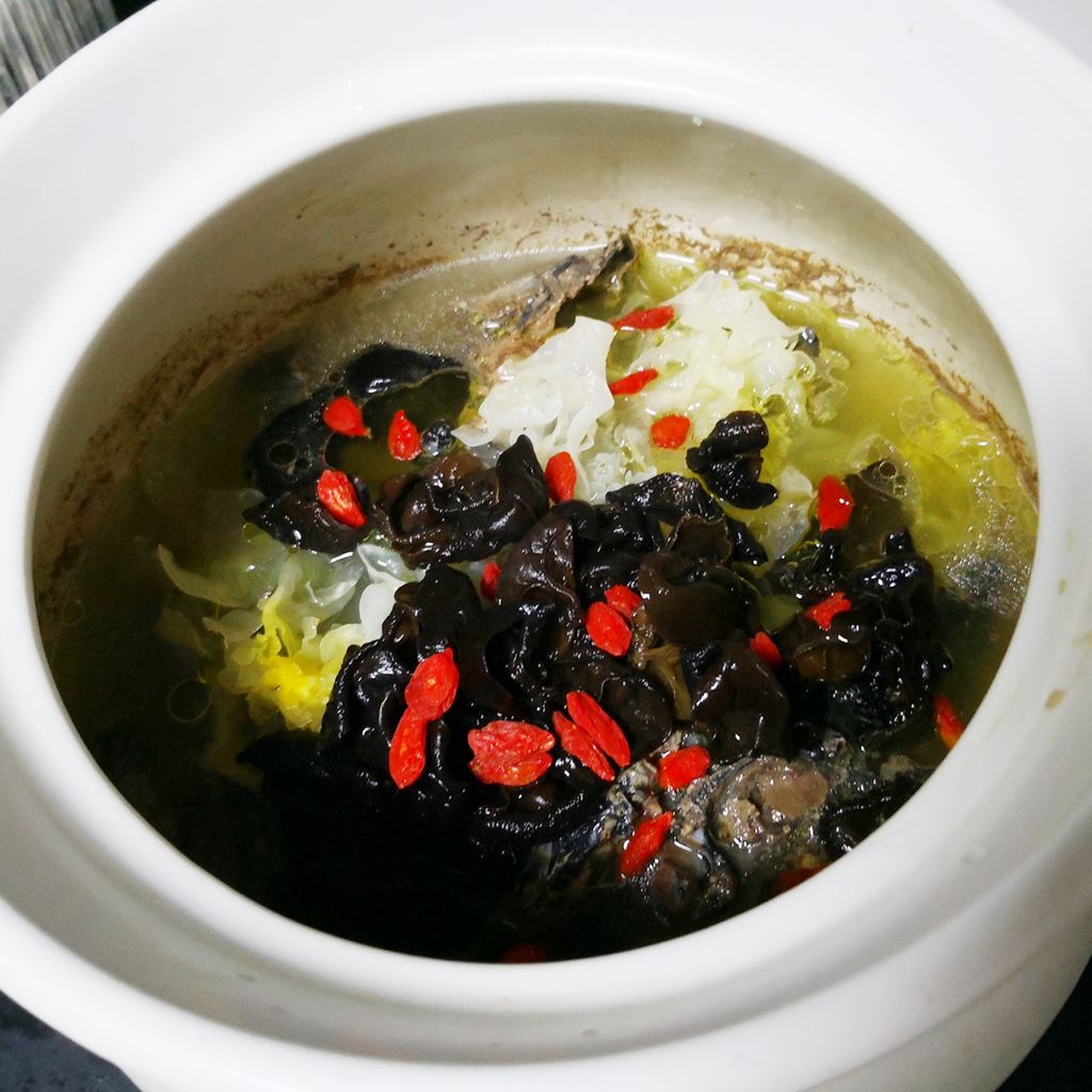 高清微距摄影:深褐色饱满黑木耳片与淡粉色瘦肉块在清澈琥珀色汤汁中悬浮,表面可见细腻胶质光泽,汤面浮有少量金黄色油脂星点,配青葱末点缀,展现传统中式养生汤品的温润质感与食材本真形态 黑木耳煲瘦肉汤成品特写