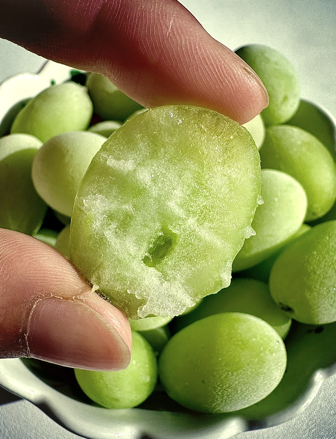 手持镊子夹起一颗刚去皮的青提果肉