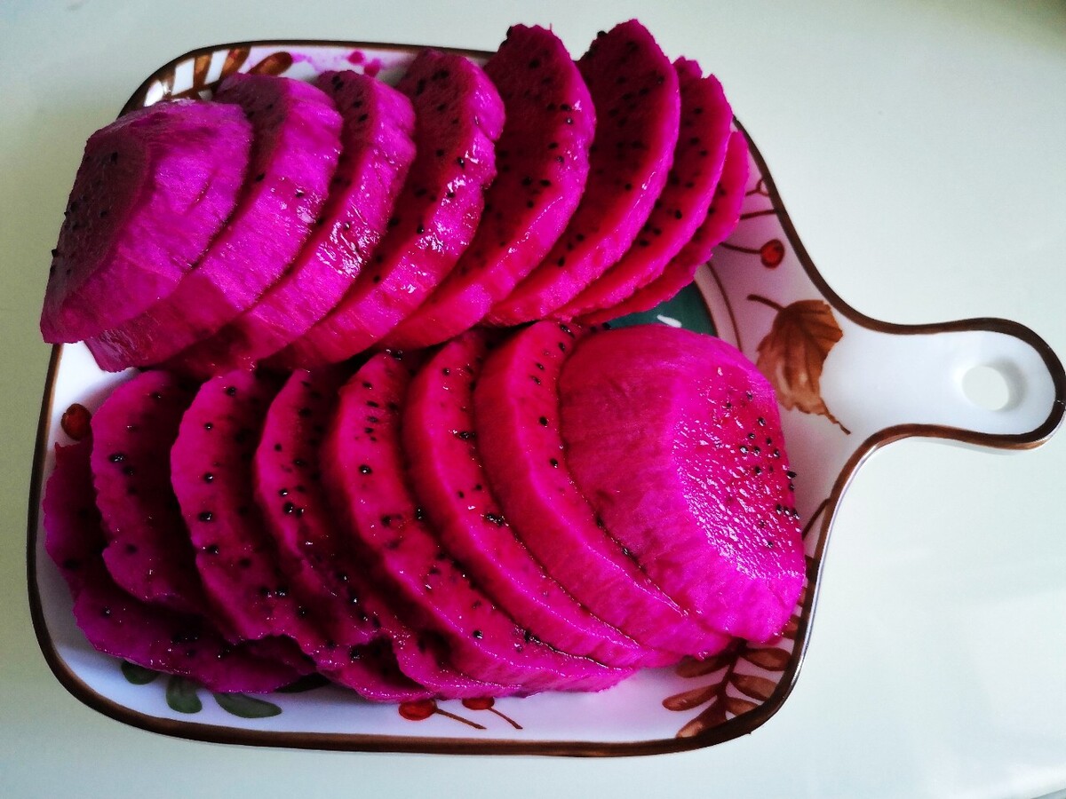 厨房中正在用刀切除火龙果腐烂部分的特写镜头