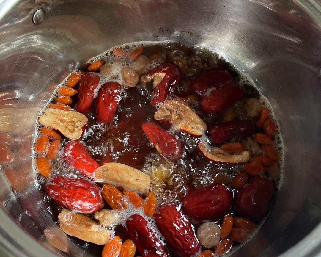 砂锅内盛放深褐色浓郁汤汁,漂浮着红色鹿茸片、浅黄鹿鞭段、枸杞与红枣,热气升腾,旁边摆放陶瓷小碗与木勺,体现家庭养生场景 鹿茸鹿鞭炖汤成品展示