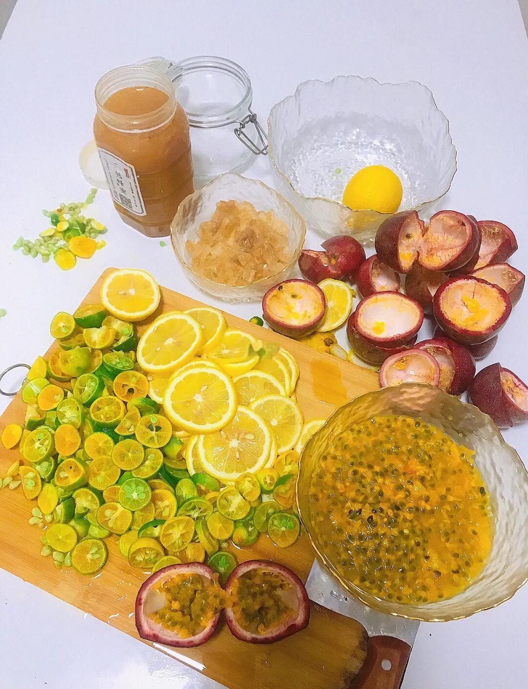 新鲜金桔与百香果并列摆放,搭配蜂蜜和玻璃杯,展示制作前的原材料准备场景 金桔与百香果摆放在木质砧板上,旁边有蜂蜜罐和玻璃茶杯,背景为自然光线厨房台面