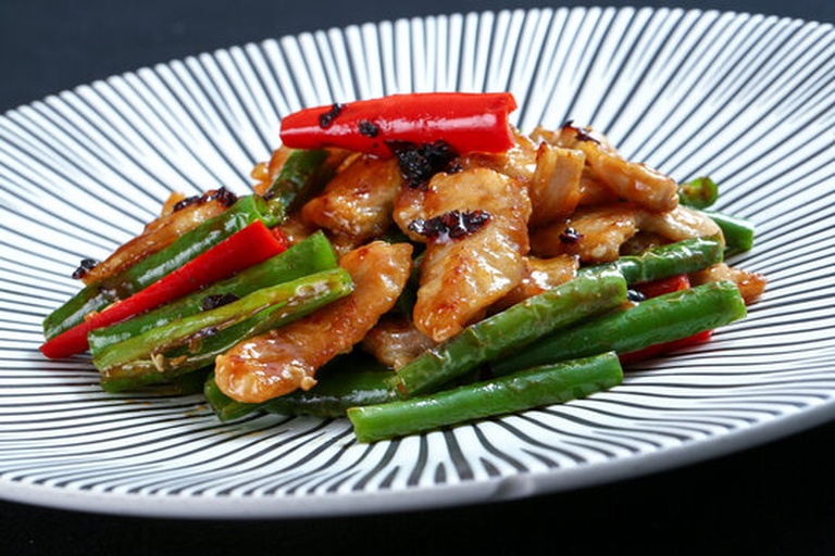 四季豆干菜经典菜肴——干豆炖五花肉成品图:砂锅内琥珀色豆条饱满吸汁,五花肉呈枣红色、肥肉晶莹半透明,汤汁浓稠挂勺,表面撒翠绿蒜末,体现干菜复水后风味浓缩与质地柔韧特性 四季豆干菜烹饪应用场景:砂锅中炖煮的干豆五花肉,豆条吸饱汤汁呈琥珀色,肉块软烂,汤面浮着细小油星,配青蒜末提香