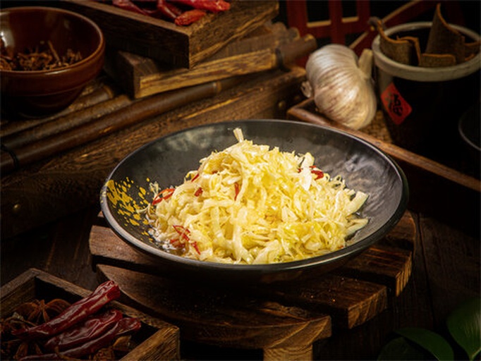 一个传统的陶制泡菜坛中盛放着大量红色的泡椒,周围可见蒜瓣、花椒、生姜等配料,泡椒表面泛着油亮光泽,液体清澈,背景为厨房木质台面,光线柔和,突出食材的新鲜与传统工艺氛围 泡椒坛子中的红辣椒与配料