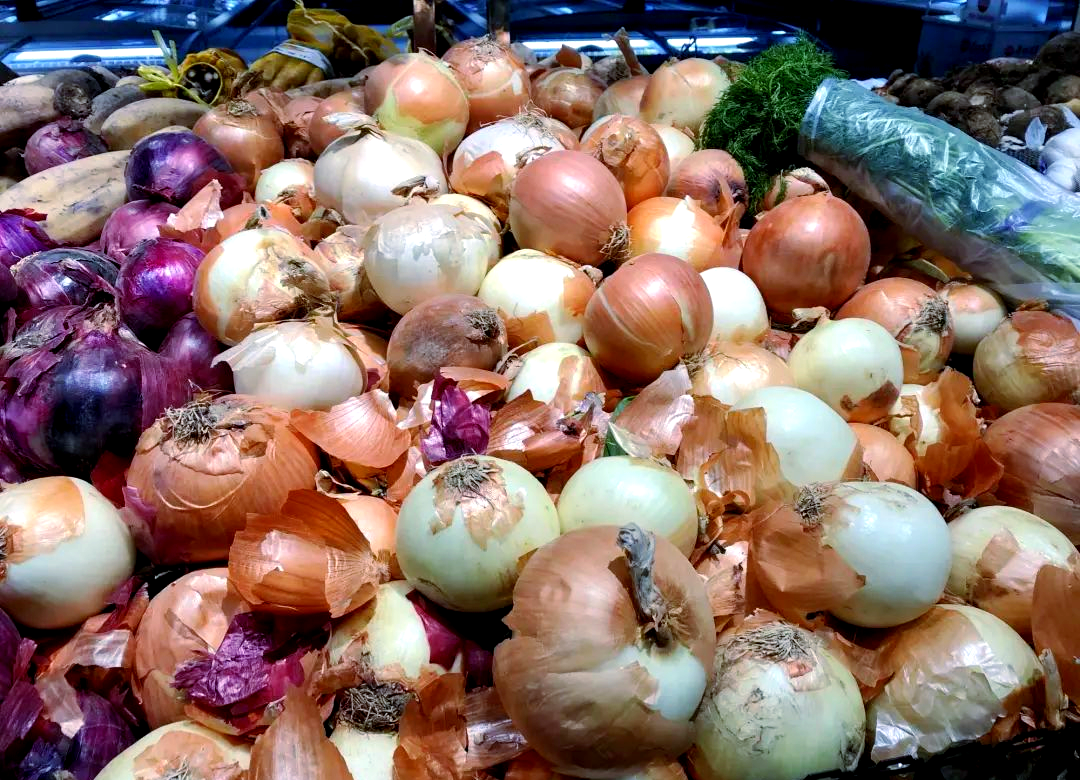 一张超市或农贸市场中洋葱陈列的照片,展示三种常见洋葱:黄色、红色(紫色)和白色洋葱整齐摆放,每种颜色分明,旁边可能标有价格标签,背景略虚化以突出主体 市场上的洋葱分类陈列图