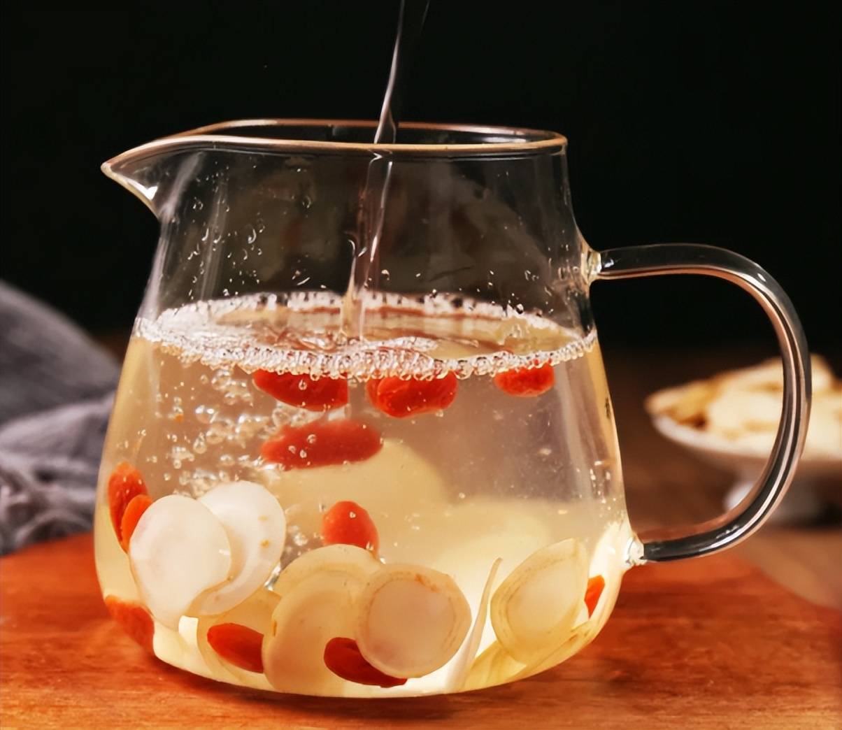 一位中年男性正在将北五味子和淫羊藿放入透明玻璃保温壶中,旁边摆放电子秤称量药材,背景为厨房台面,热水壶正在沸腾,展示科学冲泡养生茶的全过程 北五味子淫羊藿养生茶冲泡过程示意图