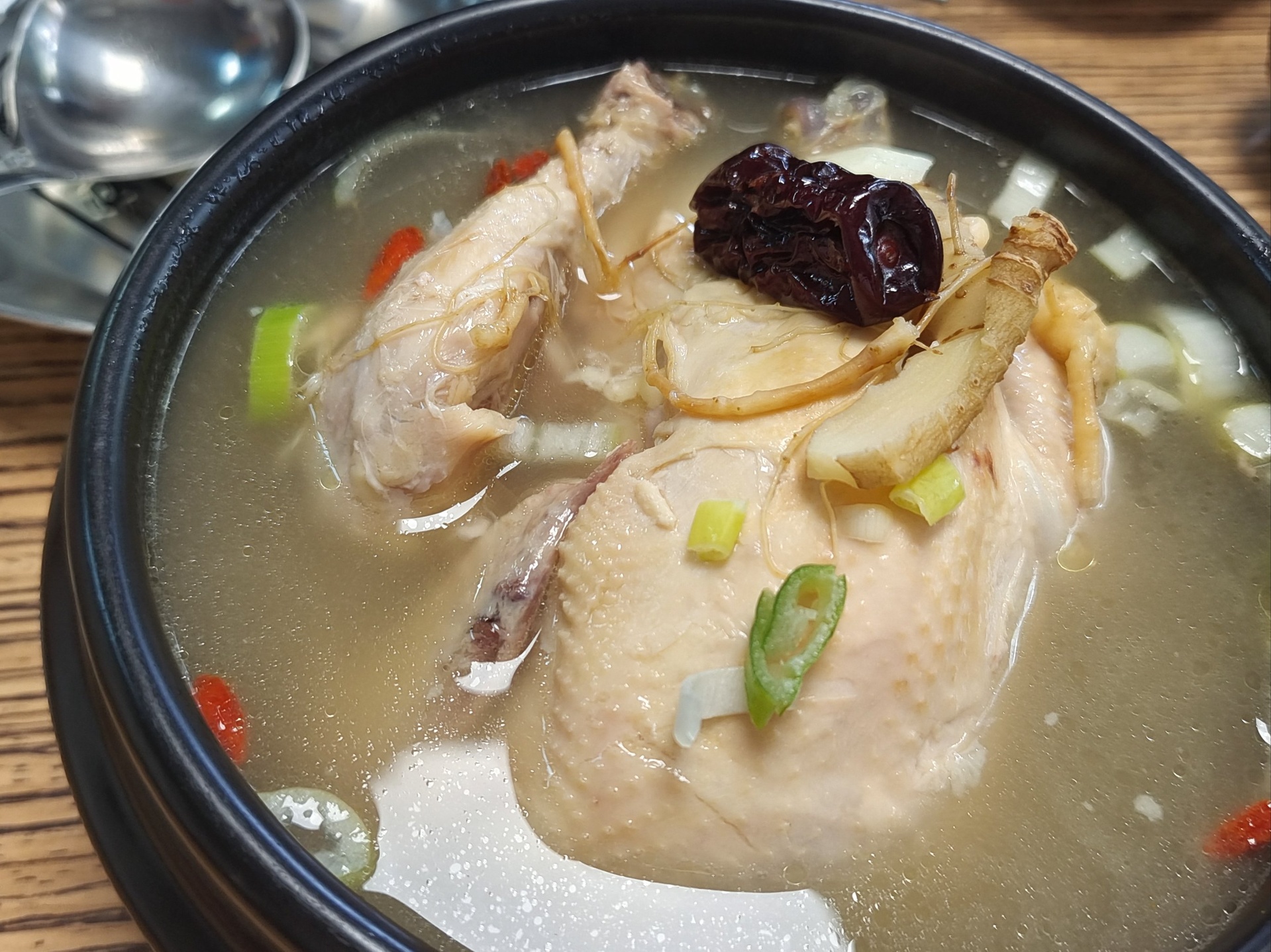 高丽参鸡汤炖煮成品特写:一碗金黄色的高丽参鸡汤,汤面油光发亮,可见完整的高丽参段、鸡块、红枣和枸杞,热气腾腾 高丽参鸡汤炖煮成品特写